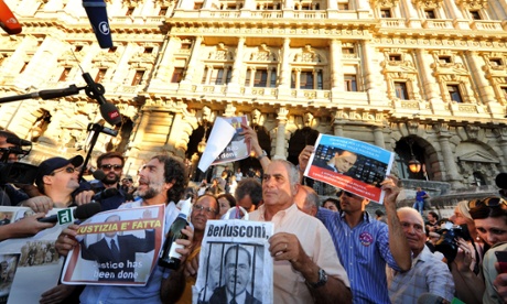 People hold signs as they celebrate the Italian Supreme Court's sentencing of Italian politician Silvio Berlusconi, in front of the Cassation building in Rome, on August 1, 2013.