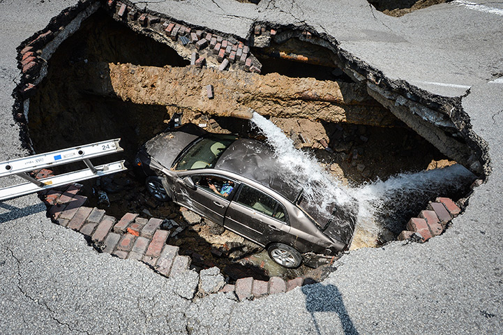 Sinkhole: Toledo, Ohio: A car at the bottom of a sinkhole caused by a broken water pi