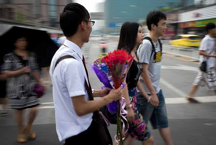 China Valentine's day: A man selling bouquets of roses approaches a couple on a street in Beijing