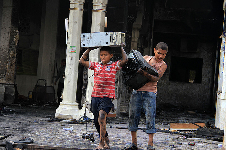 Egypt after crackdown: Children carry computer equipment in the burned remains of the Rabaa al-Ada