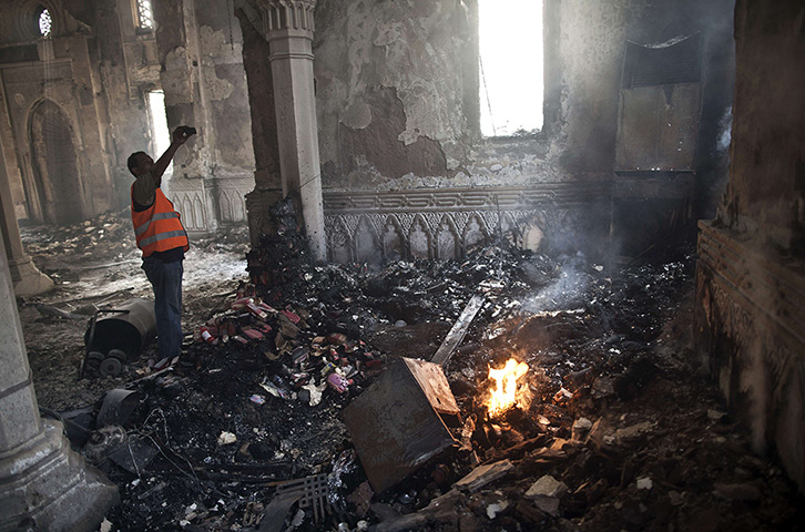 Egypt after crackdown: A man stands near a fire as he takes a picture of the damage in the Rabaa al-Adawiya mosque