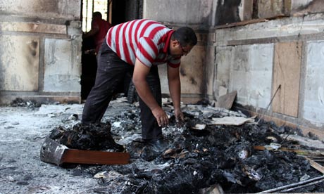An Egyptian man clears the floor in the Prince Tadros Coptic church which was set alight in Minya