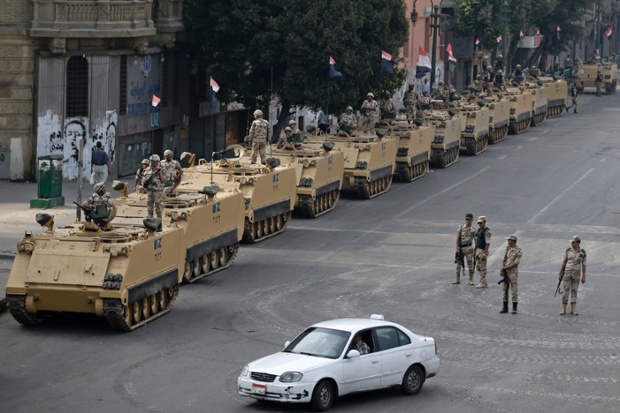 Calm after massacre: Egyptian army soldiers take their positions on top of and next to their armoured vehicles while guarding an entrance to Tahrir Square in Cairo