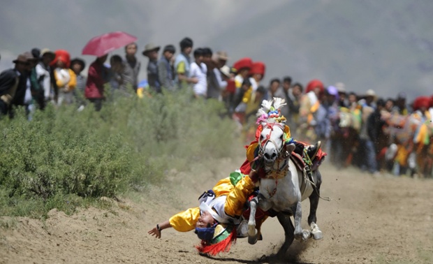 A rider competes during the annual horse racing festival in the village of Dagdong, Doilungdeqen County, Tibet Photograph: REX/Purbu Zhaxi