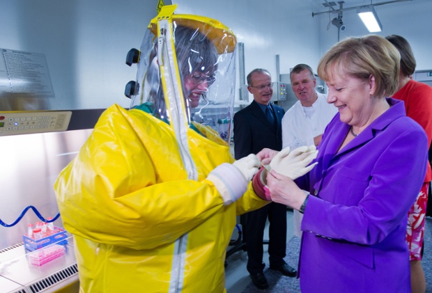 German Chancellor Angela Merkel (R) puts on a glove for veterinarian of the Friedrich Loeffler Federal Research Institute for Animal Health Anne Balkema-Buschmann (L) during the opening of the security level 4 research laboratory in Riems near Greifswald, Western Germany,. Photograph: Stefan Sauer/AFP/Getty Images
