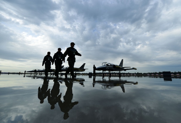 Security personnel walk past aircraft during the Karamay aviation tourism festival 2013 in Karamay, northwest China's Xinjiang region. The Breitling Jet Team and the Bayi Parachute Team of People's Liberation Army will take part in the show during the three-day festival. Photograph: Stringer/AFP/Getty Images