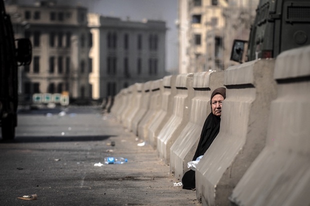 A woman shelters on Cairo's October bridge while gunfire was heard and police fired tear gas at Pro Morsi protesters. Tens of thousands of Muslim Brotherhood supporters took to the streets across Egypt in defiance of a military-imposed state of emergency following the country's bloodshed earlier this week, in Cairo. Photograph: Nameer Galal/NurPhoto/Corbis