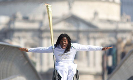 Adepitan carries the Olympic Flame over the Millenium Bridge, 26 July 2012.