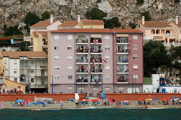 Gibraltar protests: People wave British and Gibraltar flags on the sea wall and their apartment