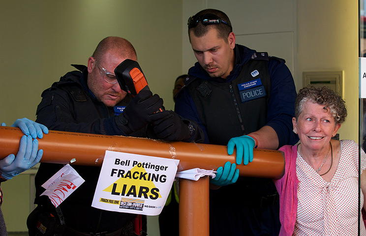 Fracking protests: A police officer uses a tool to cut through a pipe glued to the arm of a pr