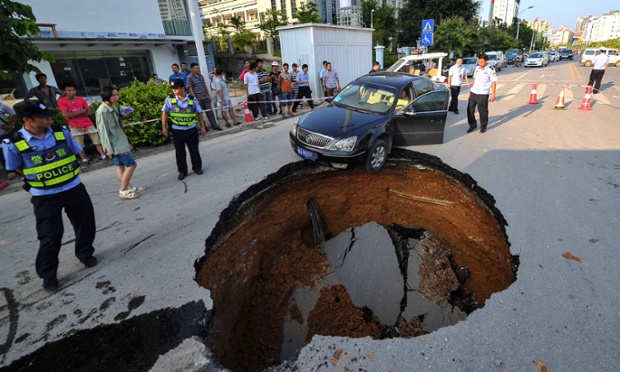 Near miss: a black car perches on the edge of a sinkhole that suddenly opened up in road, Nanjing, China. A driver had a lucky escape when they narrowly managed to avoid plunging into the 10m pit that appeared on the busy road.