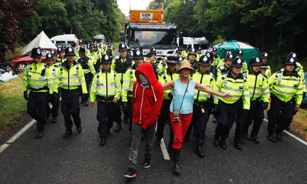 Demonstrators stand in the road as police officers escort a lorry to a site run by Cuadrilla Resources outside the village of Balcombe in southern England. Protesters have been blocking access to a drilling site in southern England as part of a campaign against the controversial 'fracking' process used in shale gas exploration.