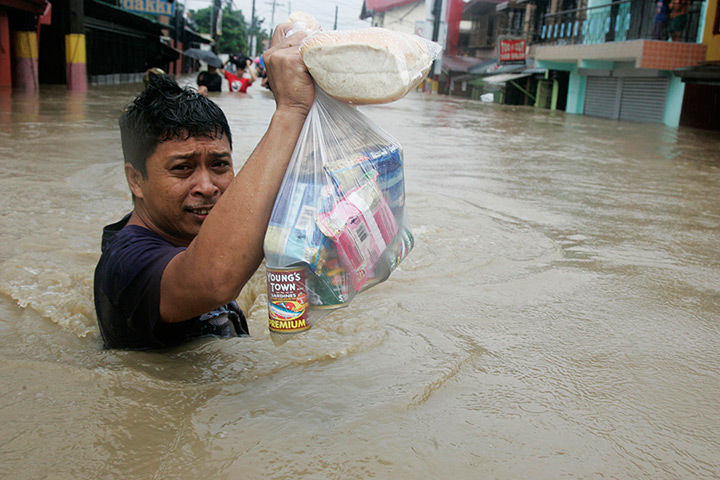 Manila floods: A man carries groceries through floodwater in Kawit town 