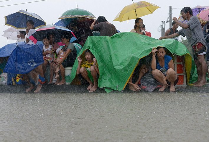 Manila floods: Residents take shelter from the rain after floodwaters inundated their home