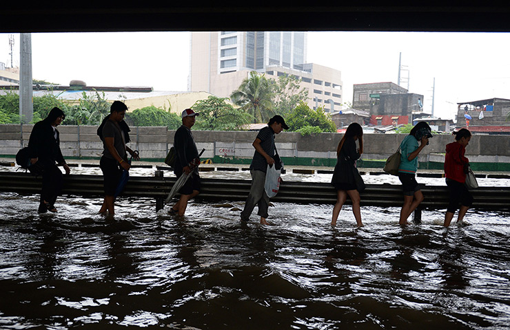 Manila floods: Pedestrians walk along a flooded road in Manila. More than half a million p