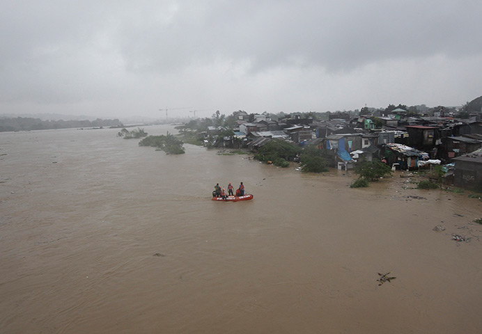 Manila floods: Rescuers ride in a dinghy along a swelling river looking for evacuees from 