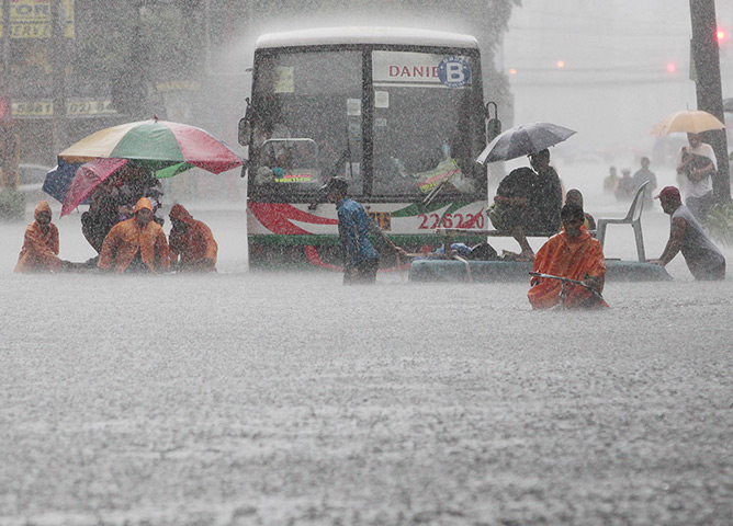 Manila floods: Office workers cross a flooded street using makeshift floats during heavy r