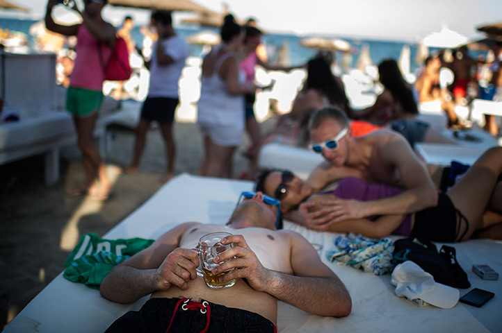 Ibiza summer: A tourist sleeps as he holds a beer at Bora-Bora Bar at the Platja d'en Bos