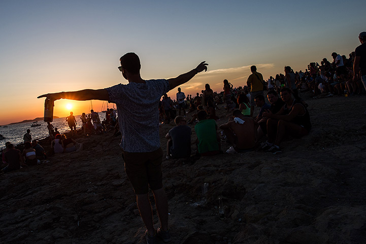 Ibiza summer: A tourist holds a can of beer as he gather watches the sunset in front of C