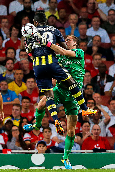 Arsenal's Wojciech Szczesny punches clear from Emmanuel Emenike 