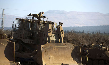 An Israeli soldier rests on his armoured bulldozer
