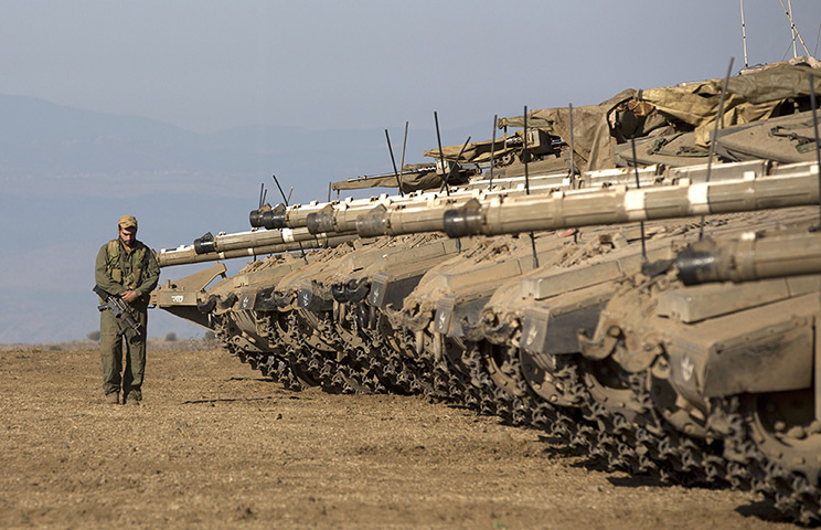 Israel preparations: An Israeli soldier walks next to Merkava tanks stationed in a deployment tr