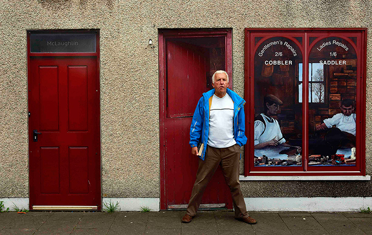 Artworks cover buildings: Man stands in front of an empty building