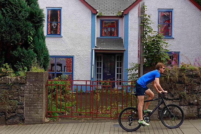 Artworks cover buildings: Boy rides his bicycle past an empty house