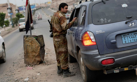A Yemeni soldier inspects a car at a checkpoint on a street leading to the US embassy in Sana'a