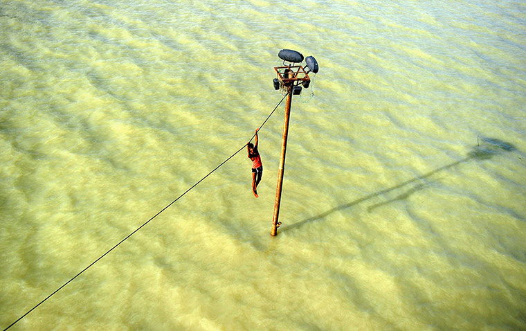 20 Photos: An Indian youth on a power line over the floodwaters of the Ganges river