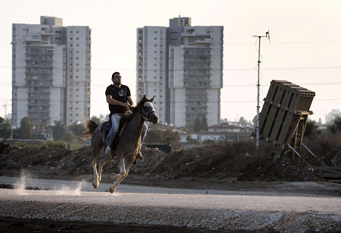 Weekend in pictures: Tel Aviv, Israel: A man rides his horse past a battery of the Iron Dome, a 