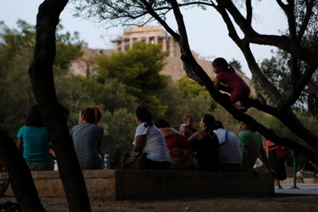 A child climbs an olive tree in front of the ancient Parthenon temple in Athens, on Monday, Sept. 9, 2013.
