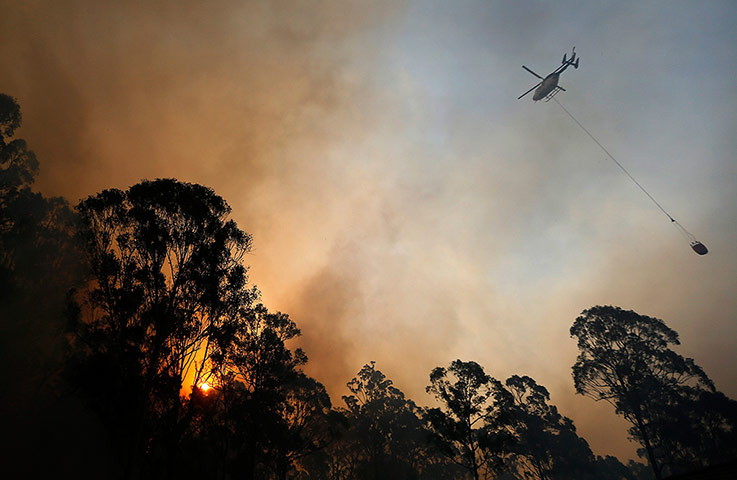 Australia wildfires: A helicopter carries water to be dropped on a bushfire