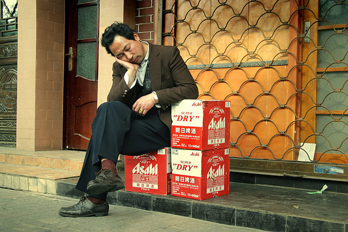 Big Picture - Daydreamers: Man sleeping next to crate of beer bottles