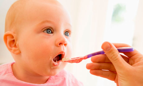 Mother feeding baby food to baby