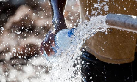 A woman using water from a spring to fill a bottle for drinking