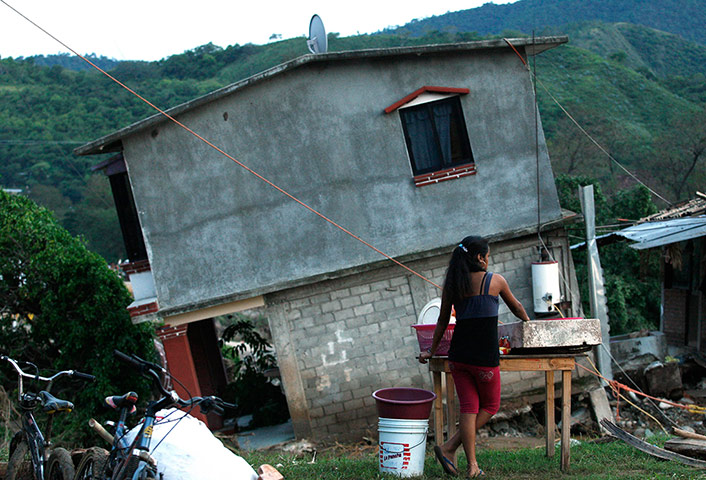 mexico floods: A woman washes dishes near a house collapsed by rains in Sola de Vega