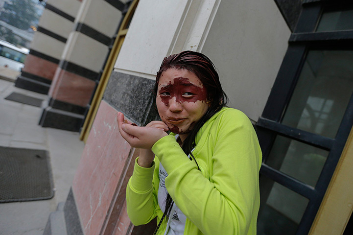 FTA: Jason Lee: A participant removes red paint from her face outside a theatre in Beijing