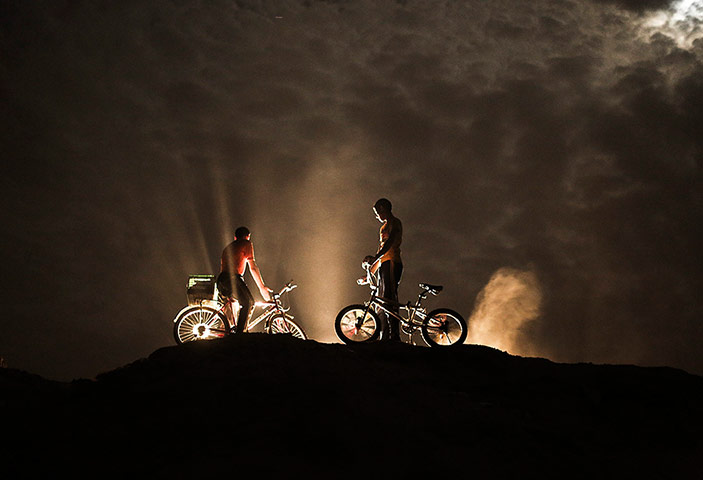 20 Years on from Oslo: Palestinian children on their bicycles are backlit by a car's headlights