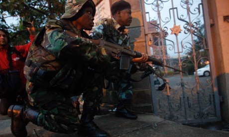 Kenya Defense Forces soldiers react to prepare for incoming fire at the Oshwal Centre adjacent to the Westgate shopping mall in the early hours of 23 September 2013.