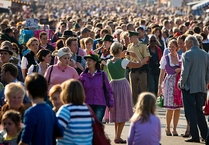 oktoberfest: Visitors walk through a crowded street during sunset 