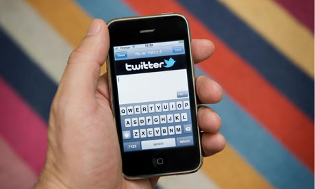 Close up of male hand holding an iPhone about to compose a Twitter Tweet. (Editorial use only).