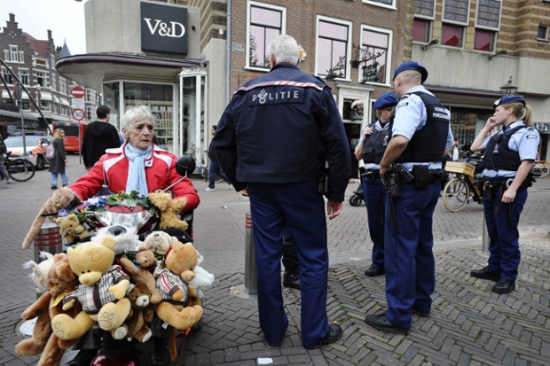 An elderly woman in an electric scooter rolls by as Dutch police gather at the site after closing two department stores and a restaurant in the city of Haarlem. The police were reacting to someone having tweeted threats of a 'bloodbath' on the social network and deployed armed police to the described sites.