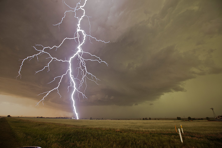 Storm cloud formations: lightning strikes a field during a storm that produced hail the size of sof