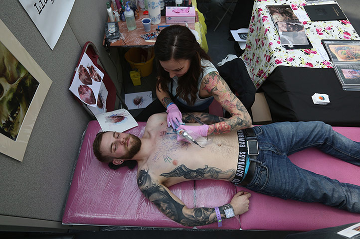 Tattoo Convention:  A tattoo enthusiast has his chest tattooed at the London Tattoo Convention