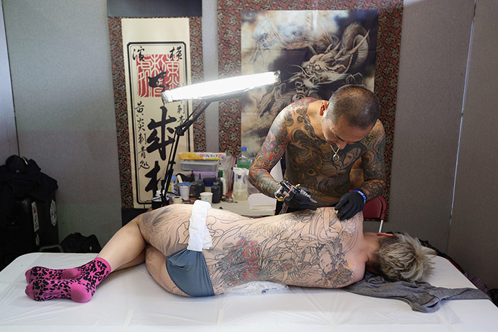 Tattoo Convention: A tattoo enthusiast has her back tattooed