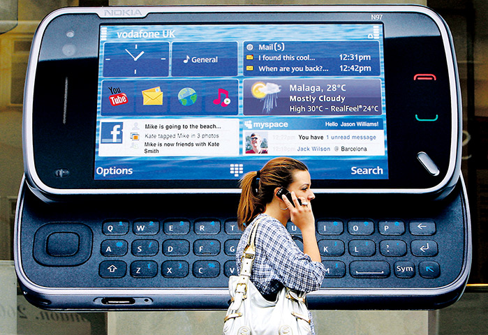 Nokia timeline: 2009: A woman uses her mobile telephone as she passes a Nokia advert for th
