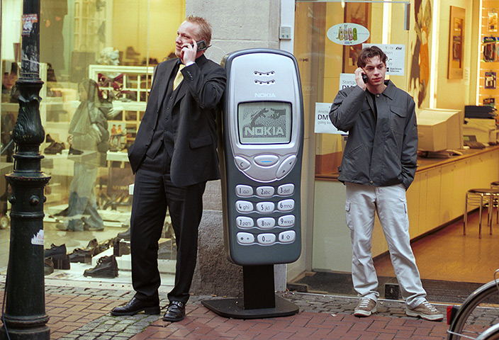 Nokia timeline: c 1998: Men stand near a large model of a Nokia 3210 in Dusseldorf