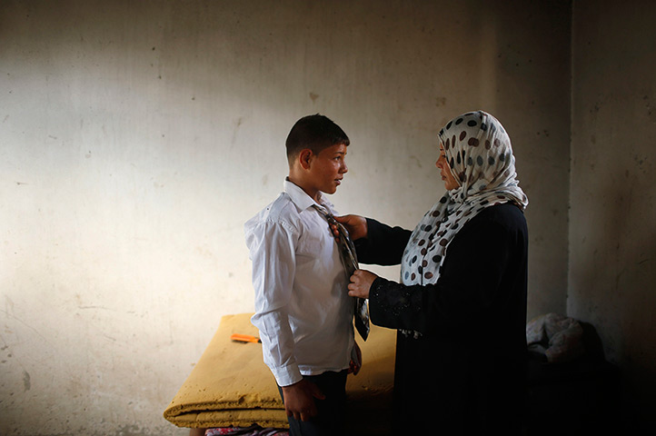 Young newlyweds: The mother of young Palestinian groom Ahmed Soboh, 15, helps him prepare fo