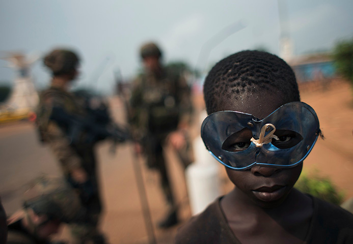 Photo highlights: A boy wears a mask as he stands near a group of French soldiers in Bangui, 